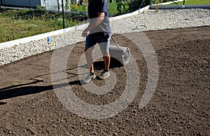 Soil preparation before sowing the lawn with a soil cultivator. soil loosening, raking, sowing. the seed is repaired by rolling wi