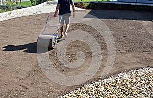 Soil preparation before sowing the lawn with a soil cultivator. soil loosening, raking, sowing. the seed is repaired by rolling wi