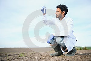 Soil Test. Indian Agronomist putting soil with garden shovel in soil sample bag outdoor. Environmental research
