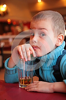 Soiled boy drinks juice from glass