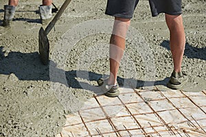 Soiled construction worker stands with his feet in concrete on a construction site