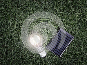 Solar cell and light bulb on green grass, energy-saving, using renewable green energy for saving the world, love and protect our