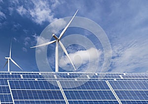 Solar cells with wind turbines generating electricity in hybrid power plant systems station on blue sky background