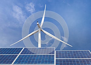 Solar cells with wind turbines generating electricity in hybrid power plant systems station on blue sky background