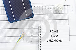 Solar cells, wires, led bulb and note pad with sign Time For Change