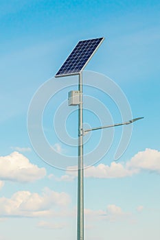 Solar device with street lamp on background of blue sky. Street light powered by solar panel with battery included. Alternative