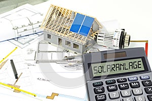 Solar energy cells on a blueprint or construction plan with calculator showing the word solar plant photo