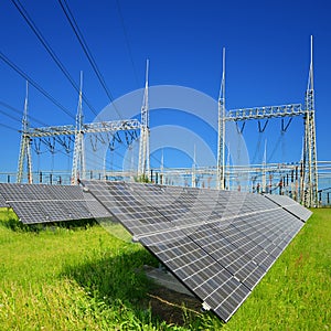 Solar energy panels in the background high voltage power substation.