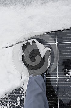 Solar energy in winter time.Getting electricity with solar panels in winter.Hands in gloves clear snow from solar panels