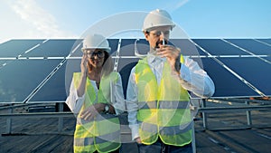 Solar installation and two inspectors standing in front of it and smiling looking into camera.