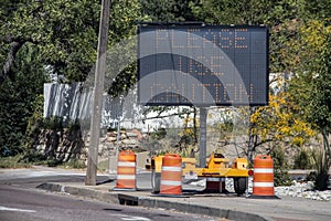 Solar mobile sign with orange cones sitting on sidewalk besides road saying Please Use Caution - Selective focus