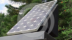 Solar panel agaist blue cloudy sky and green trees. New alternative energy technology outdoors