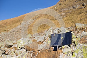 The solar panel attached to the tent. The man sitting next to mobile phone charges from the sun.