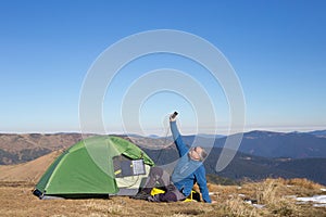 The solar panel attached to the tent. The man sitting next to mobile phone charges from the sun.