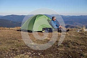 The solar panel attached to the tent. The man sitting next to mobile phone charges from the sun.