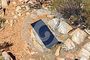 solar panel in campsite on a rock to charge phones and camera, alternative electricity source - concept of sustainable resources