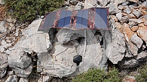 The solar panel charges the battery that lies on the rocks