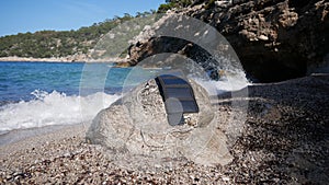 A solar panel charges a power bank by the sea