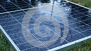 The solar panel is hosed down hard with water. The solar panel is lying on the grass