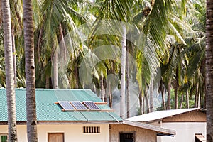 Solar panel on the house roof with a solar panels on top. House in the tropics among the palms