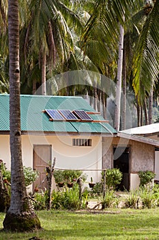 Solar panel on the house roof with a solar panels on top. House in the tropics among the palms.