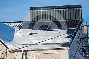 Solar panel modules are mounted on the roof of the house, covered with a layer of snow in winter