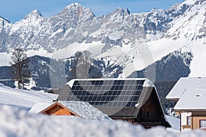 Solar photovoltaic panels PV on a snowy house roof. Electricity from the sun during winter. House in the mountains. photo