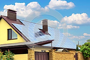 Solar panel on a red roof reflecting the sun and the cloudless blue sky. Ecological solar energy concept