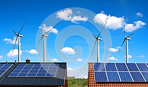 Solar panel on the roof of the house in the background wind turbines and blue sky.