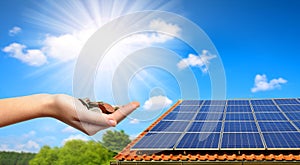 Solar panel on the roof of the house and coins in hand.