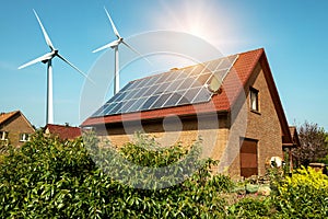 Solar panel on a roof of a house and wind turbins arround photo