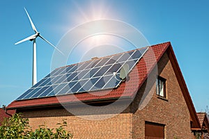 Solar panel on a roof of a house and wind turbins arround photo