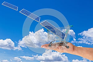 Solar panel in shopping trolley cart on women hand with photovoltaics falling from sky. photo