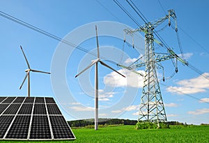 Solar panel with wind turbines and electricity pylon on meadow.