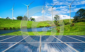 Solar panel and wind turbines farm on green hills