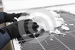 Solar panel in winter time. Getting electricity with solar panels in winter.Hands clear snow from solar panels.renewable