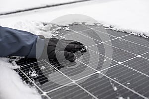 Solar panel in winter time. Getting electricity with solar panels in winter.Hands in gloves clear snow from solar panels