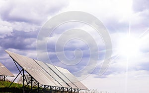 Solar panels against the background of a dark stormy sky with rays of the sun through the clouds.
