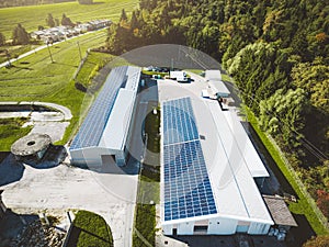 Solar panels covering the roof tops of two warehouses in the countryside