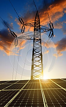 Solar panels with electricity pylon at sunset.