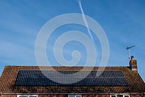 Solar panels on a house roof under a big blue sky.