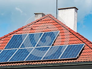 Solar panels installed on the red tiled roof of a house  Europe photo