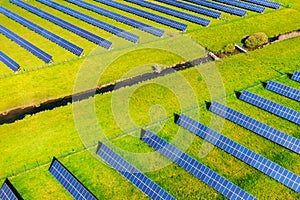 Solar panels of photovoltaic power plant from above with watercourse. Renewable resource of energy