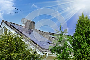 A modern house with solar panels on the roof. Clear sky, rays of the sun. Green photo