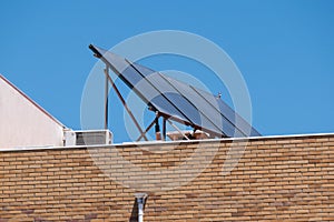 Solar panels on the roof of a brick apartment building with blue sky background.