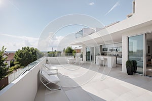 Solar panels on the roof of a modern house. Beautiful house with white kitchen, large windows and a terrace. ing