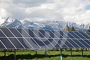 Solární panely se zasněženými horami v pozadí
