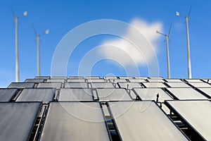 Solar panels and wind turbine against blue sky