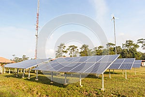 Solar panels and wind turbine with blue sky.