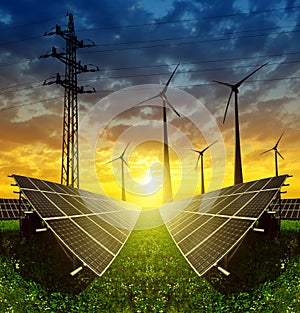 Solar panels with wind turbines and electricity pylon at sunset